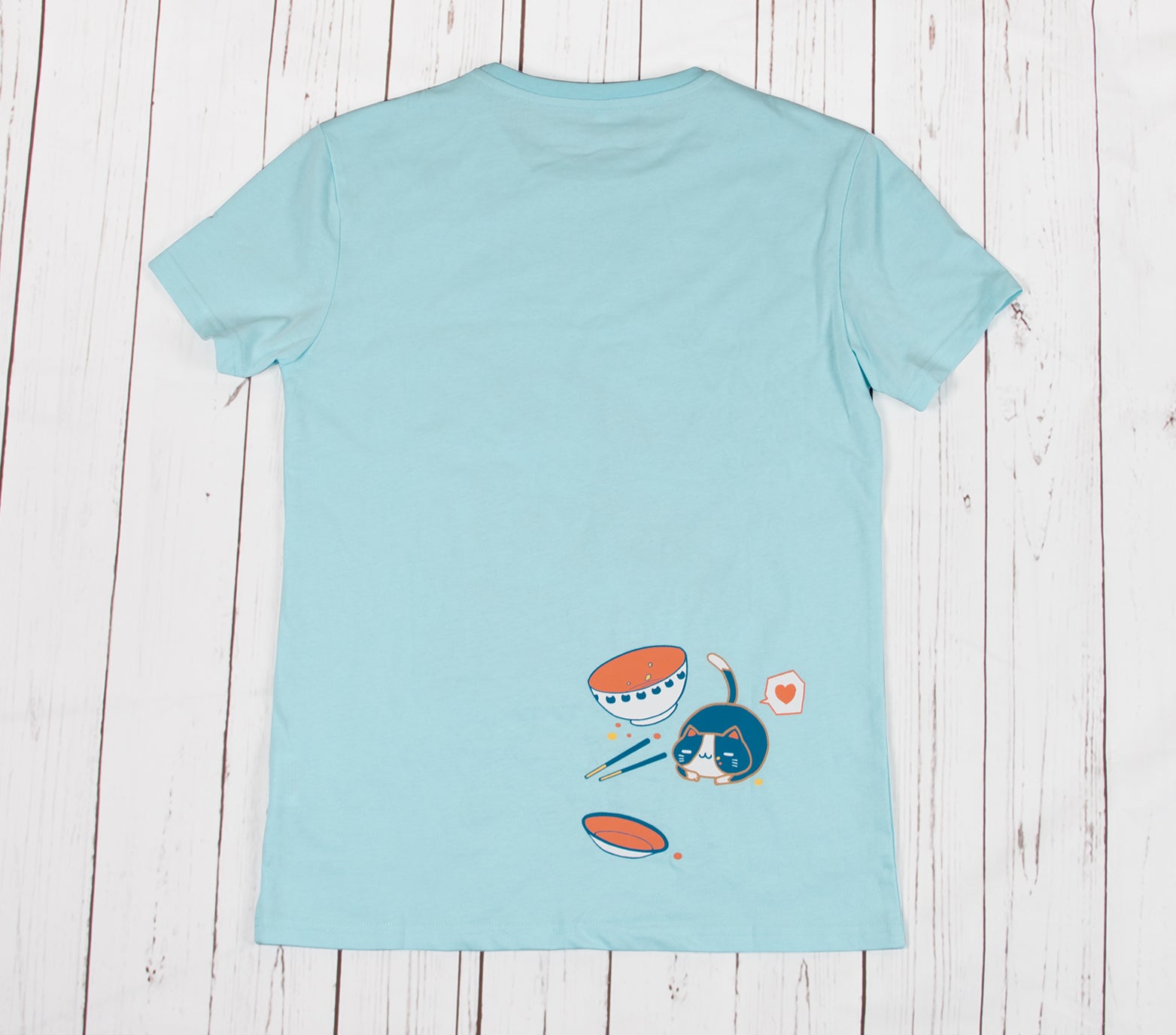 This is the back side of a mint color t-shirt that features a finished bowl of ramen and a resting cat that have just finished the bowl, showing a satisfied face. The shirt is made of 100% stretchy cotton and is available from XXS to 2XL.